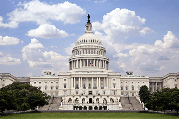 Photo of the US Capitol building with blue sky and clouds.  